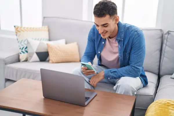 Young Hispanic Man Using Laptop Smartphone Sitting Sofa Home — Fotografia de Stock
