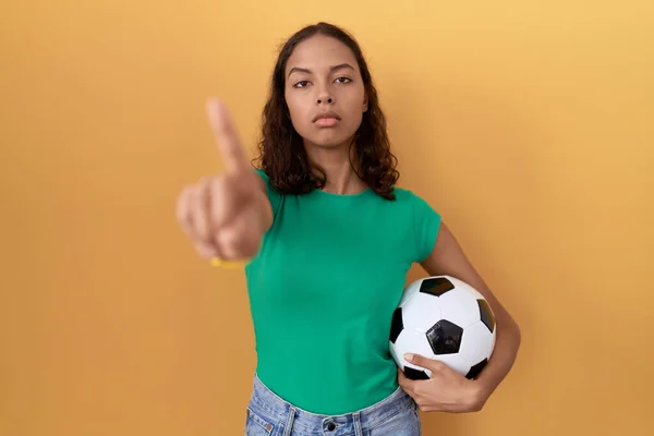 Молодая Латиноамериканка Держит Мяч Показывая Пальцем Вверх Сердитым Выражением Лица — стоковое фото