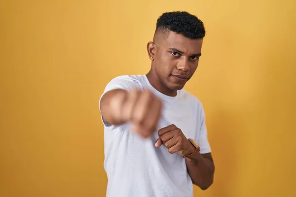 Young Hispanic Man Standing Yellow Background Punching Fist Fight Aggressive — Φωτογραφία Αρχείου