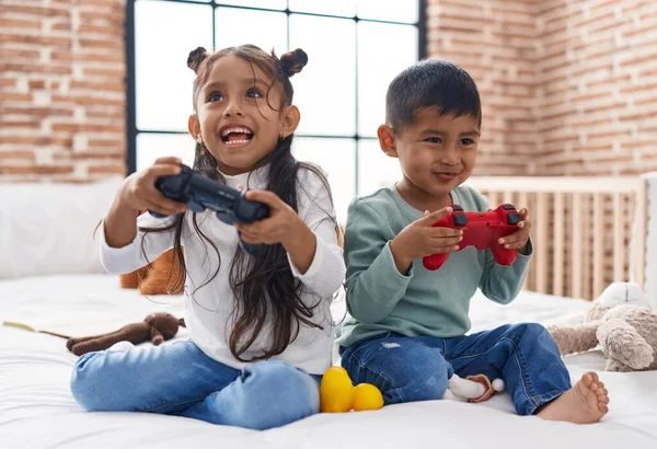可爱的男孩和女孩坐在卧室的沙发上玩电子游戏 — 图库照片