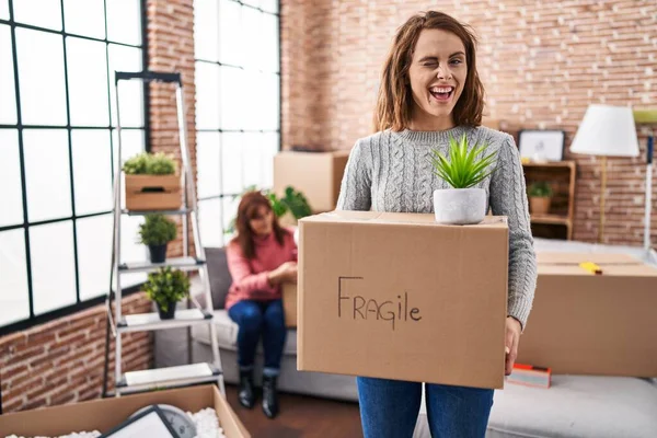 Mother Daughter Moving New Home Holding Cardboard Box Winking Looking — Stock Photo, Image