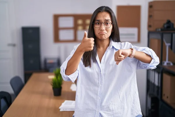 オフィスでは若いヒスパニック系の女性が親指を上下に 意見の相違や合意表現を行っています 狂気の葛藤 — ストック写真