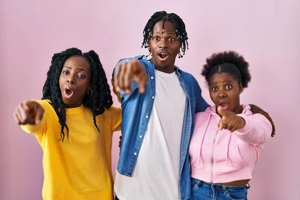 一组三个年轻的黑人站在粉红的背景上 指指点点前方的手指 张开嘴惊讶的表情 前面有什么东西 — 图库照片