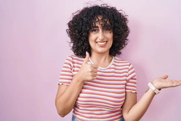 年轻的中东女人站在粉红的背景上 手牵着手 竖起大拇指做手势 笑容满面 兴高采烈 — 图库照片