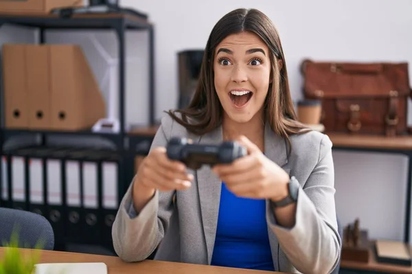 在办公室里工作的西班牙女人在玩电子游戏 一边疯狂地庆祝胜利 一边睁大双眼兴奋地尖叫着 — 图库照片