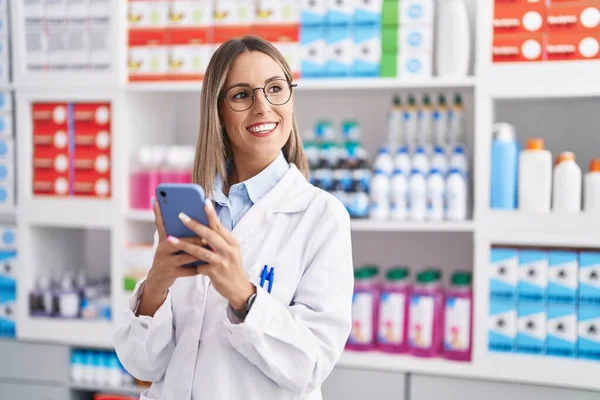 stock image Young beautiful hispanic woman pharmacist using smartphone working at pharmacy