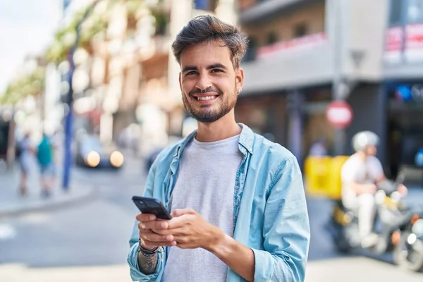 Fiatal Spanyol Férfi Mosolygós Magabiztos Segítségével Smartphone Utcán — Stock Fotó