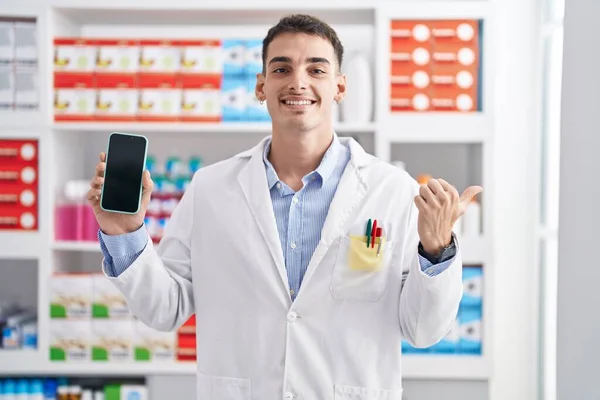 Hombre Hispano Guapo Trabajando Farmacia Mostrando Pantalla Del Teléfono Inteligente —  Fotos de Stock