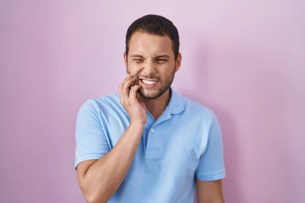 西班牙裔男子站在粉红的背景上用手摸着嘴 由于牙痛或牙病而面带痛苦 — 图库照片