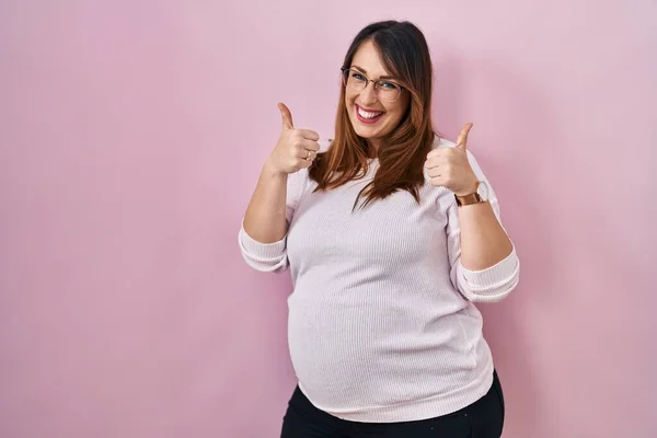 Těhotná Žena Stojící Nad Růžové Pozadí Znamení Úspěchu Dělá Pozitivní — Stock fotografie