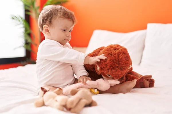 Sevimli Sarışın Bebek Elinde Oyuncak Bebekle Yatakta Oturuyor — Stok fotoğraf