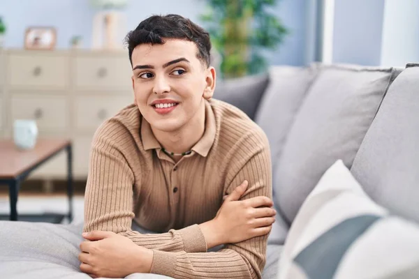 Young non binary man smiling confident lying on sofa at home