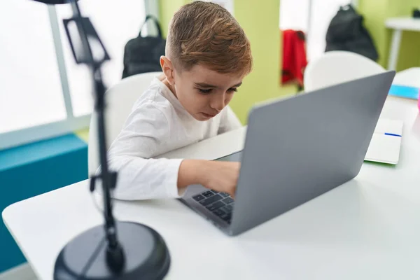 stock image Adorable hispanic boy student using laptop sitting on table at classroom