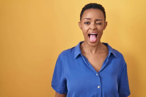 Африканская Американка Стоящая Жёлтом Фоне Торчащая Языком Довольна Смешным Выражением — стоковое фото