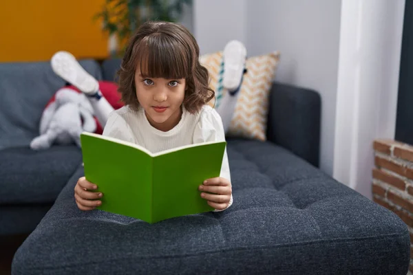 Adorable Hispanic Girl Reading Book Lying Sofa Home — Stok fotoğraf