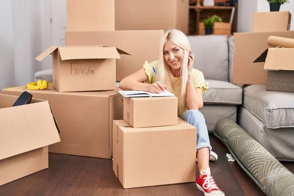 Young Blonde Woman Writing Notebook Sitting Floor New Home — Stockfoto
