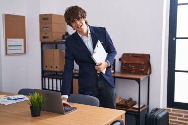 Ofiste dizüstü bilgisayar kullanan genç sarışın bir iş adamı.