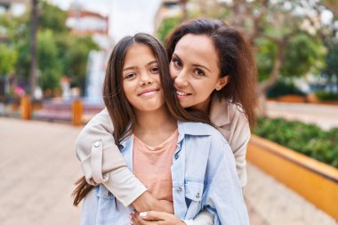 Woman and girl mother and daughter hugging each other at park
