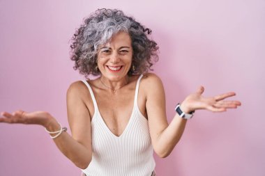 Middle age woman with grey hair standing over pink background celebrating crazy and amazed for success with arms raised and open eyes screaming excited. winner concept 