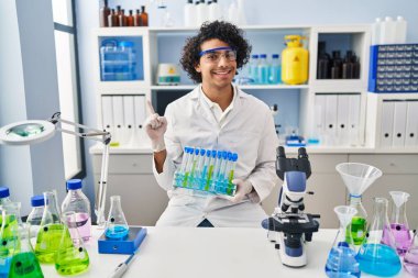Kıvırcık saçlı İspanyol adam, bilim adamı laboratuvarında çalışıyor. Gülümsüyor, gülümsüyor. 