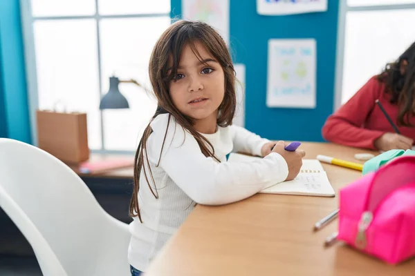 Adorable Hispanic Girl Student Sitting Table Writing Notebook Classroom — Foto de Stock
