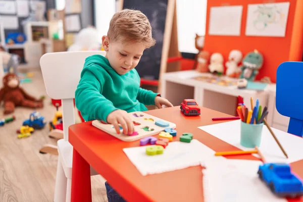 可愛いですCaucasian男の子遊びとともに数学パズルゲーム上のテーブルの上に座って幼稚園 — ストック写真