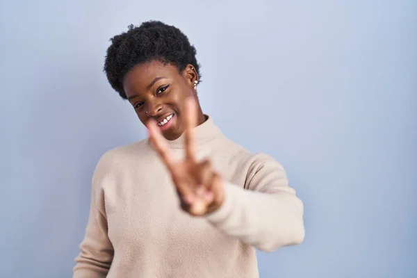 Африканская Американка Стоящая Синем Фоне Улыбаясь Смотрит Камеру Показывая Пальцы — стоковое фото
