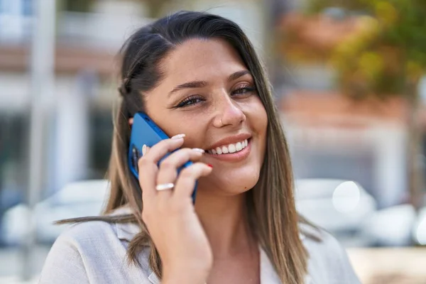 若いヒスパニック系の女性が路上でスマートフォンで自信を持って話して笑顔 — ストック写真