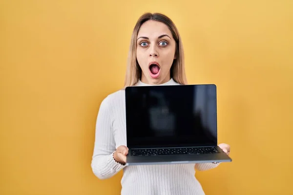 Jovem Loira Segurando Laptop Com Medo Chocado Com Expressão Surpresa — Fotografia de Stock