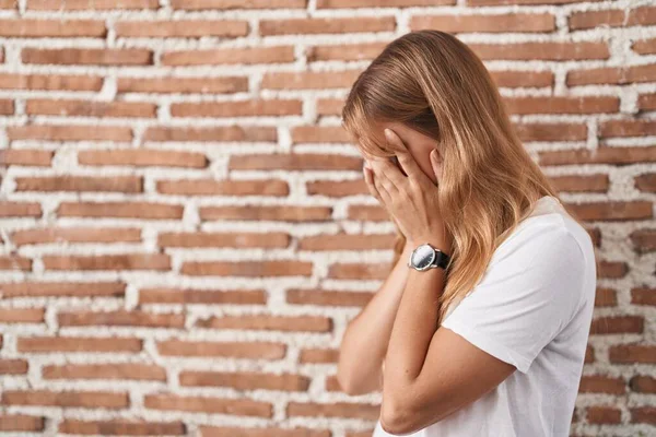 泣きながら手で顔を覆う悲しい表情でレンガの壁の上に立つ若い白人女性 うつ病の概念 — ストック写真