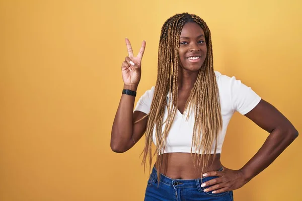 Sarı Arka Planda Örülmüş Saçları Olan Afro Amerikalı Kadın Kameraya — Stok fotoğraf