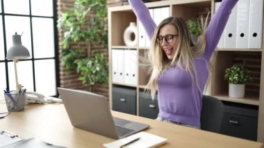 Genç sarışın iş kadını ofiste şampiyon ifadesi olan dizüstü bilgisayar kullanıyor.