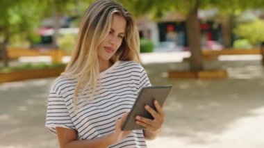 Parkta dokunmatik ped kullanan genç sarışın kadın.