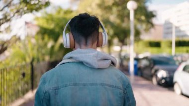 Genç İspanyol adam arka planda müzik dinliyor ve parkta dans ediyor.
