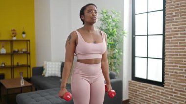 African american woman using dumbbells training at home