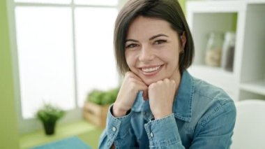 Beyaz bir kadın evde masada kendinden emin bir şekilde gülümsüyor.