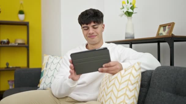 Young Hispanic Man Watching Video Touchpad Sitting Sofa Home — Stockvideo