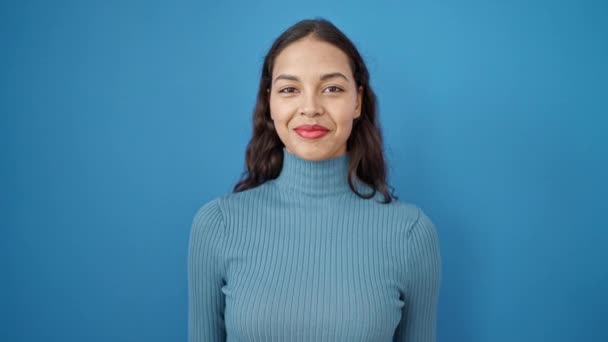 若い美しいヒスパニック系の女性は 孤立した青の背景の上に新しい車のキーを指して自信を笑顔 — ストック動画