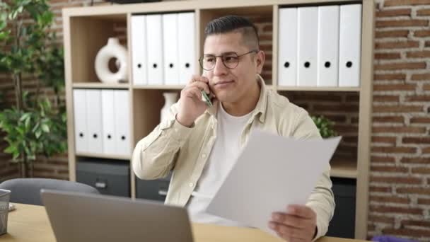 若いヒスパニック系の男ビジネス労働者はオフィスで電話読書文書で話す — ストック動画