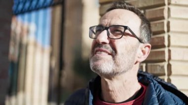 Middle age man smiling confident looking to the sky at street