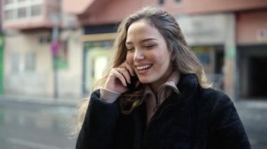 Young beautiful hispanic woman smiling confident talking on smartphone at street