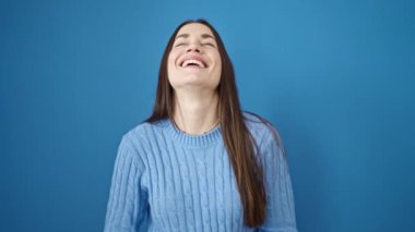 İzole edilmiş mavi arka planda duran kendine güvenen beyaz bir kadın.