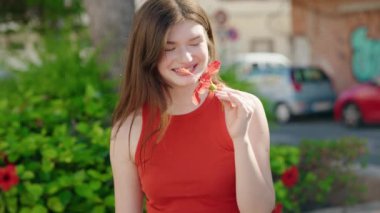 Young caucasian woman smiling confident wearing flower on ear at park