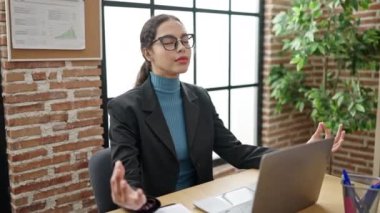 Young beautiful hispanic woman business worker doing yoga exercise at office