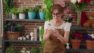 Çiçekçide videocuda kendine güvenen orta yaşlı bir çiçekçi.