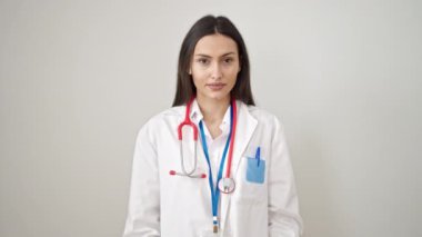Genç, güzel İspanyol kadın doktor, soyutlanmış beyaz arka planda bilgisiz duruyor.