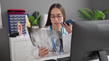 Genç, güzel, İspanyol bir doktor elinde x-ray 'le klinikteki akıllı telefondan sesli mesaj yolluyor.