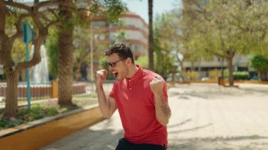 Genç İspanyol gözlüklü adam parkta dans ediyor.