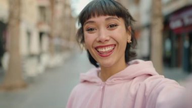 Young hispanic woman smiling confident having video call at street