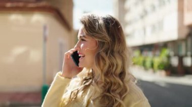Genç sarışın kadın gülümsüyor. Kendine güveni tam. Akıllı telefondan konuşuyor.